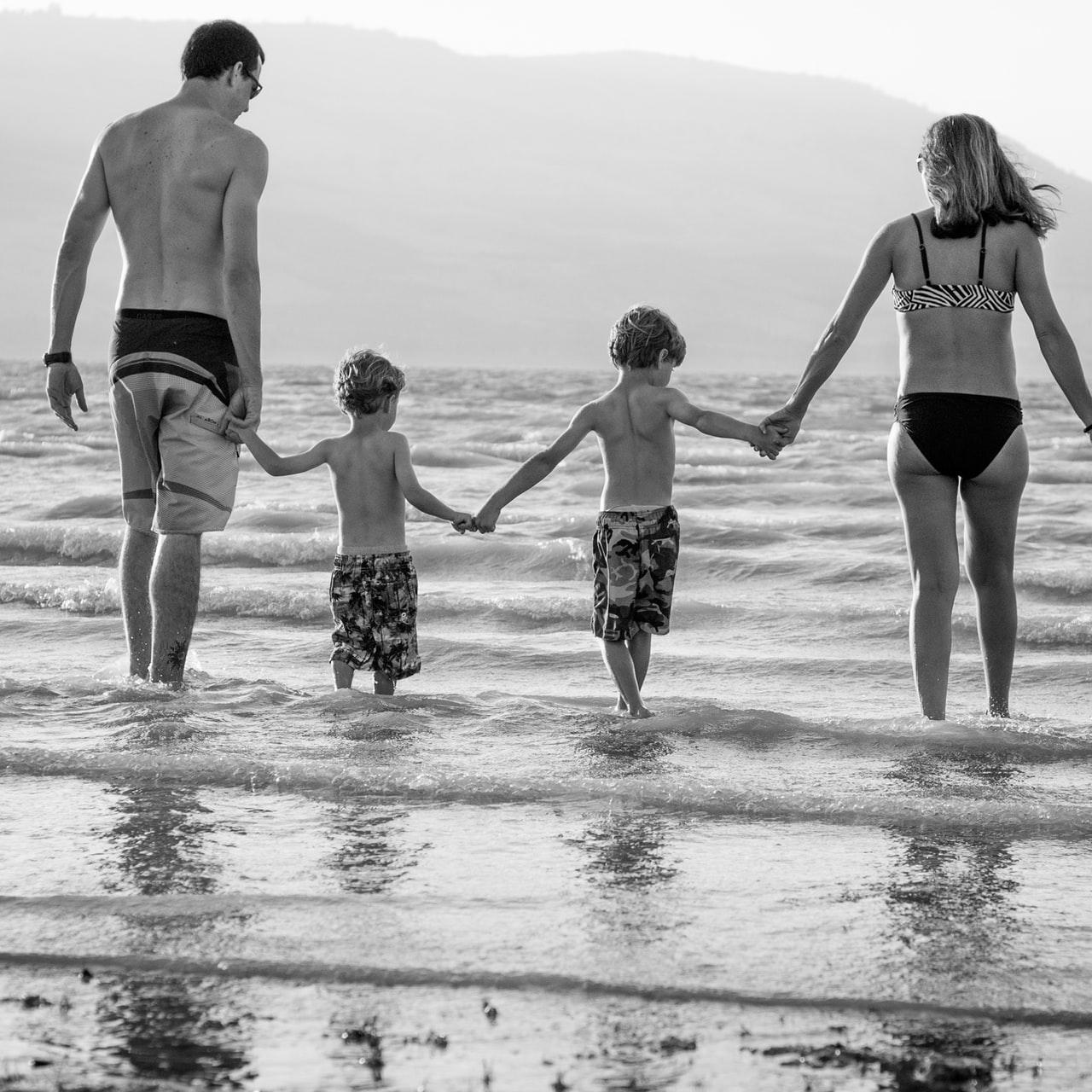 grayscale photography of family walking on beach